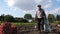 An old farmer gathers potatoes in a field. Grandpa in the garden, chickens behind him