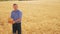 Old farmer man baker holds a golden bread and loaf in ripe wheat field. slow motion video. harvest time. old man baker