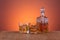 Old fashion glass and carafe with whisky drink on warm, orange background and wood