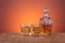 Old fashion glass and carafe with whisky drink on warm, orange background and wood