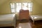 Old fashioned bedroom with two beds and a cupboard under the sunlight from the windows