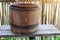 Old-fashioned brown wooden vintage Asian water tank, placed on a wooden table, bamboo wall background.