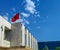 Old fashioned communist socialist European small town government architecture building with Albanian flag and blue sky above on