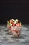 Old-fashioned English dessert Eton mess with raw strawberries, cream and meringues in glasses on dark background side view