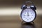 Old fashioned metal alarm clock on a gold background.