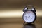 Old fashioned metal alarm clock on a gold background.