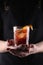 Old fashioned Negroni cocktail in hand on the black background