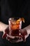 Old fashioned Negroni cocktail in hand on the black background