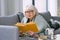 Old fashioned senior woman laying on the couch reading a book.