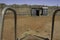 An old-fashioned slide in front of abandoned thunderbox-syle toilets and tennis courts