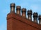 Old fashioned traditional clay chimney pots on a red brick support against a blue sky