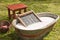 An old fashioned washing trougth filled with water, a vintage washboard and soap that wash the laundry