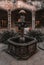 Old-fashioned water fountain with flowerpots in a stone-paved outdoor courtyard