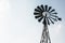 Old-fashioned wind pump against pale blue sky