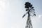 Old-fashioned wind pump against pale blue sky