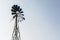 Old-fashioned wind pump against pale blue sky