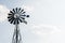 Old-fashioned wind pump against pale blue sky with white clouds