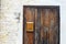 Old fashioned wooden door, rusty postbox and white brick and concrete wall background