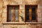 Old fashioned wooden window with bars on stone wall