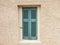 Old fashioned worn window with green wooden shutters, closed, on plastered wall background