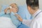 An old fat asian male patient with gray hair wearing eyeglasses and light blue shirt have runny nose and try to blow the snot out