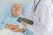 An old fat asian male patient with gray hair wearing eyeglasses and long sleeve light blue shirt laying down on hospital bed