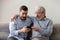 Old father and son using phone, shocked by unexpected news