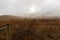 An old fence crosses a dreary, foggy, empty, and barren winter landscape at the National Bison Range wildlife refuge, Montana, USA