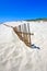 Old fence sticking out of deserted sandy beach dunes