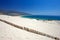 Old fence sticking out of deserted sandy beach dunes