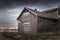 Old finnish barn on a cold evening in sunset with a Sorbus (Mountain-ash) in front with dark clouds