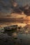 Old fisherman boat. Seascape. Fishing boat at the beach during sunrise. Low tide. Water reflection. Cloudy sky. Slow shutter speed