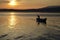 An old fisherman on the lake at sunrise