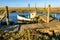 Old fishing boat moored at jetty on coastal river in marshland
