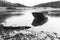 An old fishing boat is moored on the water. Black and white photo. Dramatic landscape