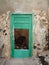 Old flaking green busted door in white wall in Fuerteventura Canary Islands