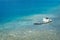 Old forgotten wooden boat rotting in the shallow turquoise waters of the bay. Transparent blue water with rocks on the bottom