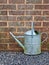 Old galvanized watering can by wall.