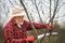 Old gardener in panama hat cutting tree branches.