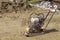 Old gasoline compactor stands on the sand.