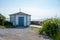 An old gazebo painted white and blue stands by the ocean in the small fishing village BarsebÃ¤ckshamn in southern Sweden