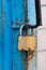 Old gold padlock covered with rust on a blue door