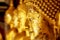 Old and golden face of golden Buddha statue on blurred golden Buddha statue stand strong line background