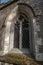 Old gothic arched carved leaded window in an old church with flint walls