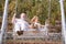 Old grandfather and young child grandson swinging in garden outdoors. Grand dad and grandson sitting on swing in park.