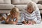 Old grandma little grandkid drawing pictures lying on warm floor