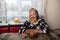 Old grandmother sits at a table in her village hut in front of sweets