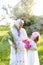 Old grandmother standing with little granddaughter and keeping flowers.