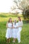 Old granny standing with adult granddaughters in white dresses.