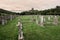 Old gravestones and crosses in a graveyard or cemetery, with castle ruins in distance under a brooding dramatic sky